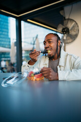 Young man eating fresh fruit salad in a modern food court