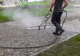 Professional cleaning service worker power washing cobblestone