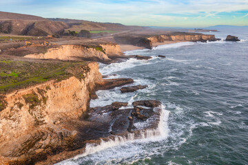 Aerial view of beautiful sandy beach and cliffs of Pacific Ocean coast on Highway 1 in California, Davenport, Santa Cruz. Travel concept, tourism, recreation, vacation