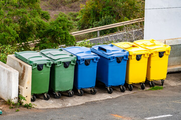 A row of trash cans are lined up on the side of the road