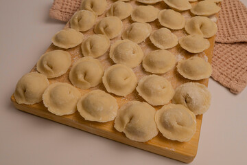 Homemade meat dumplings are laid out on a board.