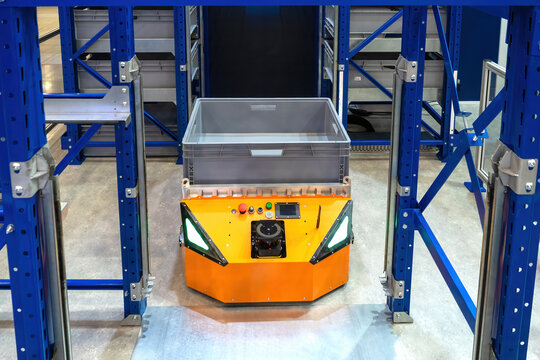 Warehouse robot. Automated guided vehicles. AGV among warehouse racks. Autonomous mobile robot. Storage machines in distribution center. Warehouse robot for transporting boxes. Modern storage tech