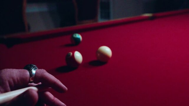 Closeup of a player hitting Poll balls game on a red table with a blurred player in the background
