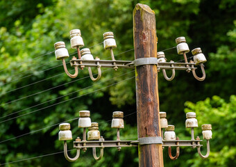 le haut d'un vieux poteau électrique en bois avec des supports isolants en faïence pour les cables