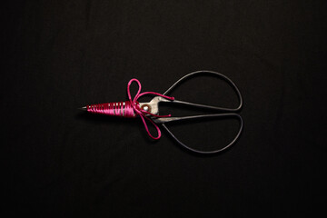 Ornate Scissors Wrapped with Bright Pink Thread on a Dark Background