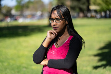 Fototapeta premium Latin transgender woman with thoughtful expression in a park