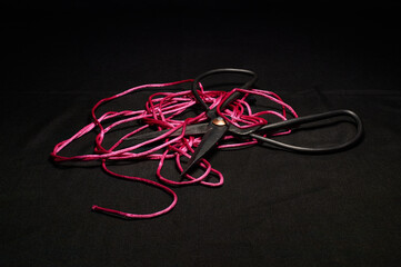 Scissors and Vivid Red Twine Against a Dramatic Dark Background