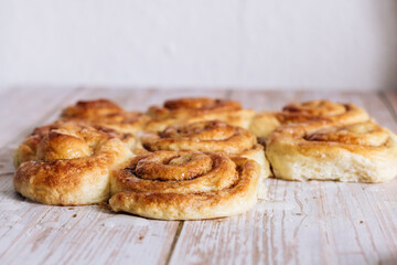 Golden brown cinnamon rolls with a glaze rest on a table, attracting with their shiny surface.