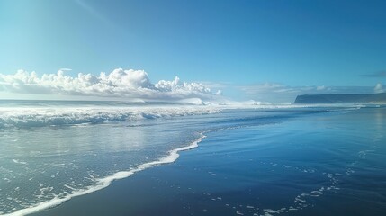 Obraz premium Blue ocean waves with a slight reflection of the sky, gently splashing as they meet the coastline. 