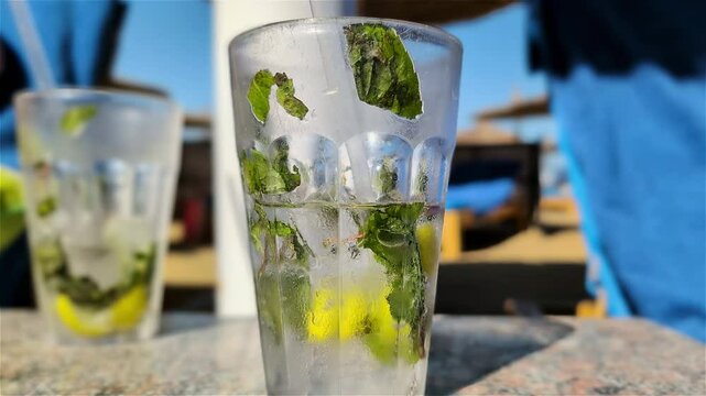 Close-up of moving away from mojito in transparent cups with straw on the beach under the parasol in an all-inclusive vacation