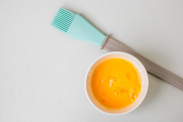 A bowl of whisked egg yolks with a silicone brush, perfect for baking and Easter preparations