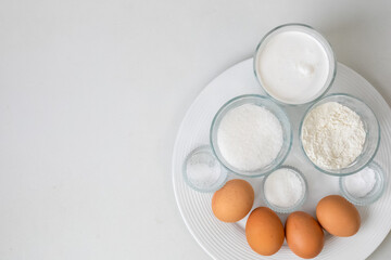 Top view of baking ingredients like eggs, flour, and sugar arranged on a plate, ideal for Christmas baking preparations