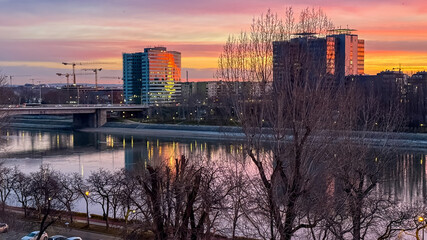 Cityscape along a riverside at sunset, reflecting urban development and tranquility, ideal for...