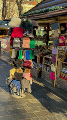 Obraz premium A vibrant European Christmas market stall offers colorful winter hats and souvenirs, embodying holiday spirit and shopping tradition