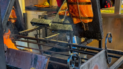 Traditional Nordic-style salmon is being smoked over an open fire at a festive market, highlighting outdoor cooking techniques