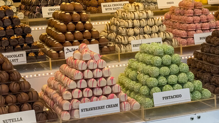 A variety of colorful chocolate truffle pyramids displayed in a festive European market stall, perfect for Christmas indulgence