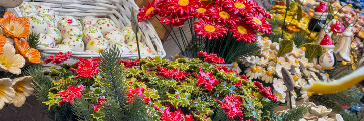 Colorful ceramic flowers and decorative ornaments on display at a market, symbolizing festive spirit and holiday gift shopping