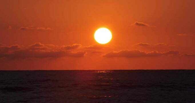 Captivating footage of a golden sunset over the Black Sea, filmed at the serene Ureki coastline in Georgia. The sun gently dips into the horizon, painting the sky with warm hues of orange and red, whi