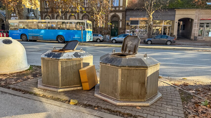 Urban waste management challenge depicted by overflowing garbage bins with cardboard boxes on a...