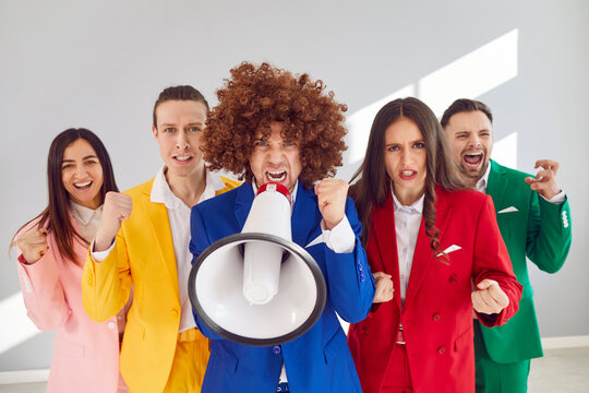 Man shouting into megaphone surrounded by enthusiastic supporters cheering and fist-pumping. People in colorful suits make bold statement. Concept of communication, leadership, protest and team spirit