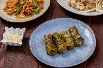Couscous with vegetables, udon noodles with meat in spices and dolma on a wooden table