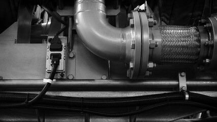 piston gas engine electric generator with many valves and pipes. The engine is orange and has many valves.