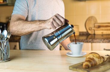 Warm light and cozy atmosphere in the kitchen. Caucasian man just waking up is served coffee with...