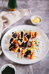 Christmas salad herring under a fur coat on skewers on a plate on the table vertical view