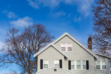 Classic gabled house with bare trees on a winter day in Brighton, Massachusetts, USA