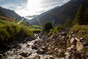Scenic mountain landscape in Tyrol, Austria. Rolling green hills, rugged alpine peaks, and a clear blue sky capture the peaceful beauty of the summer Alps.