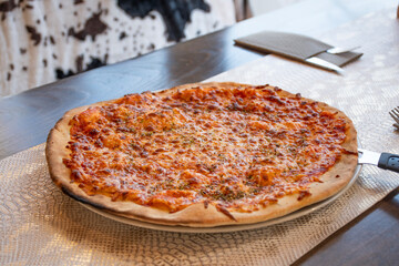 margherita pizza with cheese and homemade tomato sauce in a restaurant top view with cutlery on the table at an angle