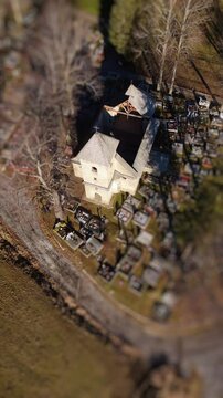 Vertical Aerial Tilt-Shift View of an Old Church in the Middle of a Cemetery in Rural Landscape,