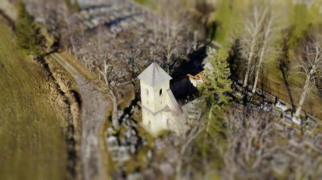Aerial Tilt-Shift View of an Old Church in the Middle of a Cemetery in Rural Landscape, Rotating View
