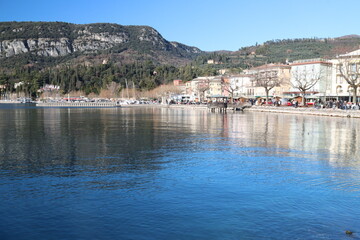 Garda lake waterfront reflecting on calm water in winter sun