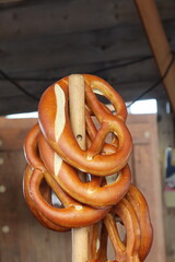 Freshly baked pretzels hanging on wooden stick in rustic setting