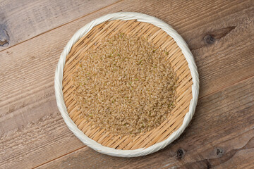 木目の背景に竹笊に盛られた玄米の俯瞰