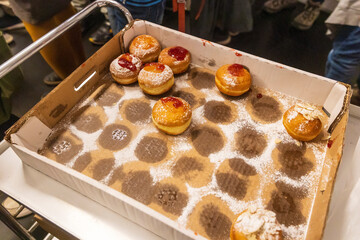 Sufganiyot with jam, dusted with powdered sugar, in a cardboard box.