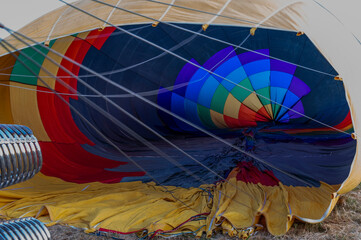 Obraz premium A close-up view of the colorful interior of a deflated hot air balloon, showcasing its vibrant patterns as it lies on a grassy field in Tuscany, ready for inflation.