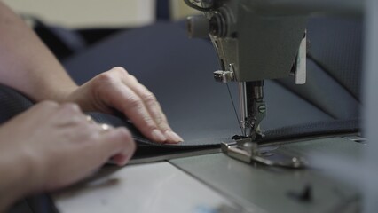 experienced worker works sewing machine. sew leather goods. hands close up. workshop business concept. female hands sew clothes sewing machine. professional seamstress workshop. clothing production