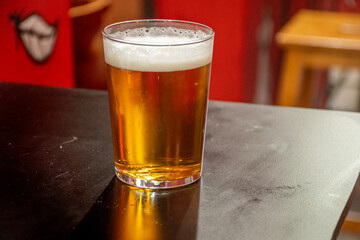 craft beer with foam served on street table in El Tubo alley in Zaragoza in Spain with red blurred background