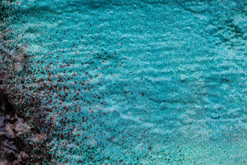 Close-up of an uneven wall spray painted with bluish cyan and black colors. Abstract full frame textured grunge graffiti background with copy space.