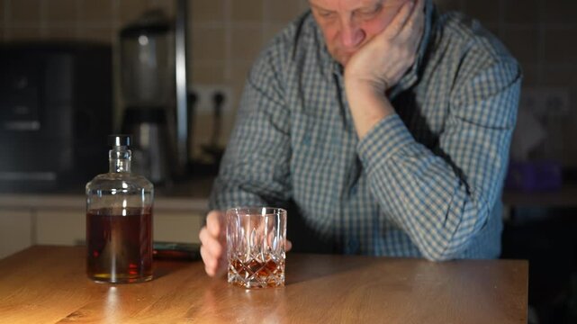 Man pushes the glass of whiskey away from him with a confident movement of his hand. With this gesture, he indicates that he will no longer drink alcohol. Alcoholism, sad depressed man refuses alcohol