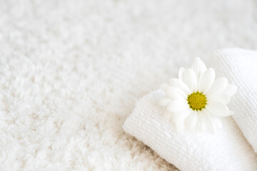 White towels with chamomile flower and aroma lamp, candle on background. Spa and wellness or beauty salon, romantic relaxation concept. Intimate hygiene. Copy space.