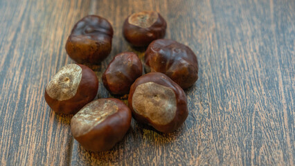 A bunch of chestnuts rests on a smooth, homogeneous background, highlighting their rich, glossy shells. Perfect for showcasing seasonal flavors or healthy snacking. Space available for text.