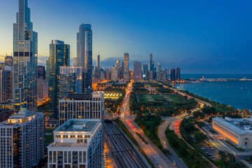Chicago skyline at twilight, illuminated skyscrapers, traffic on Lake Shore Drive, and city park. Urban landscape. Downtown, Chicago, Illinois, United States