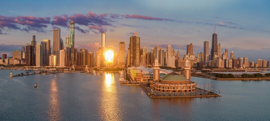 Obraz premium Chicago skyline at sunrise, reflecting on the water. Stunning aerial view of the city's iconic architecture and Navy Pier. Golden hour light. Navy Pier, Chicago, Illinois, United States