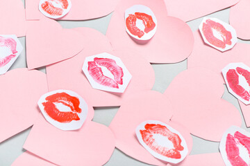 Composition with pink paper hearts and lipstick kiss marks on grey background. Valentine's Day celebration