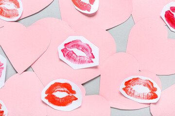 Composition with pink paper hearts and lipstick kiss marks on grey background, closeup. Valentine's Day celebration