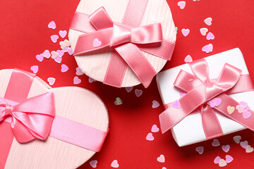 Beautiful gift boxes with confetti on red background. Valentines Day celebration