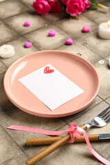 Beautiful table setting for Valentine's Day with blank card, hearts and candles on grey tile background